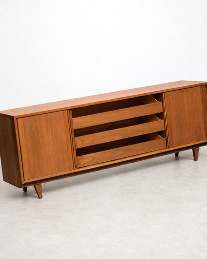 Rear three-quarter view of the sideboard with one sliding door open, revealing interior shelving.