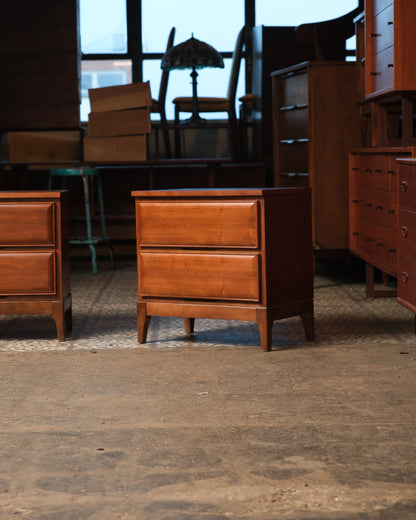 Front view of one walnut nightstand with two drawers, shown in a furniture showroom setting.