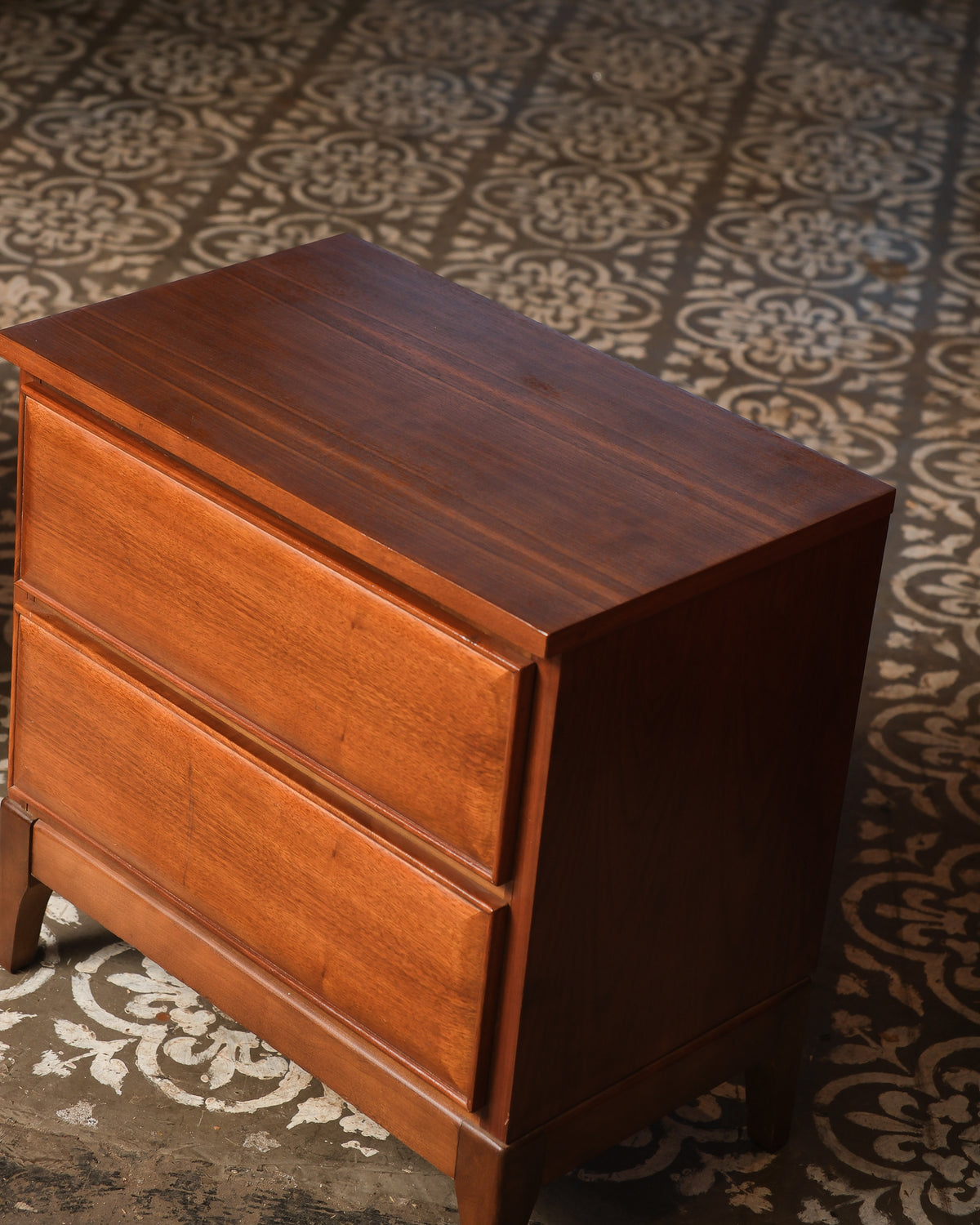 Angled overhead view of a walnut nightstand showing the top grain and drawer fronts.