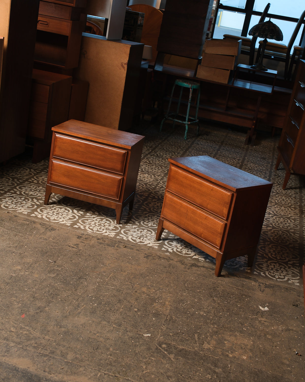 Two matching walnut nightstands shown side by side in a showroom setting.