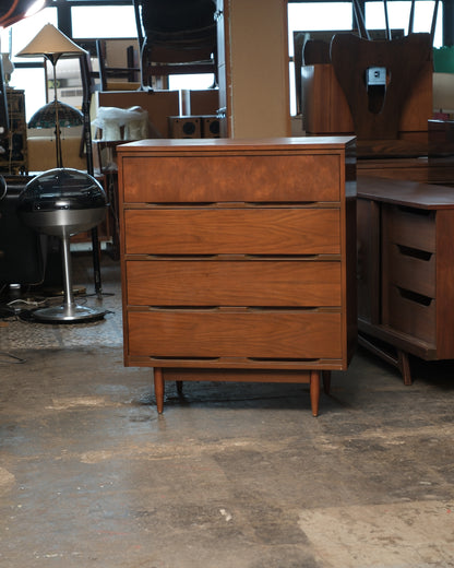 Mid-century modern walnut 4-drawer tallboy dresser, front view on a warehouse floor.