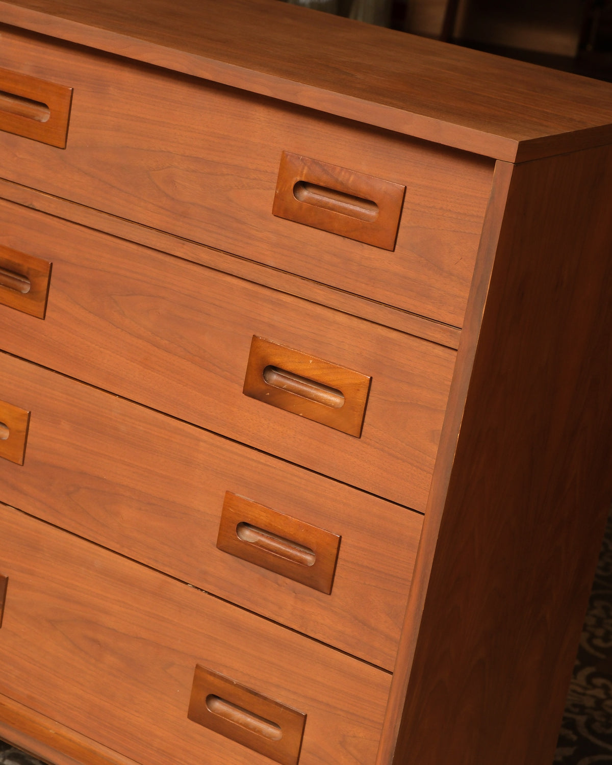 Close-up of the recessed sculpted wood pulls and drawer joinery on the tallboy dresser.