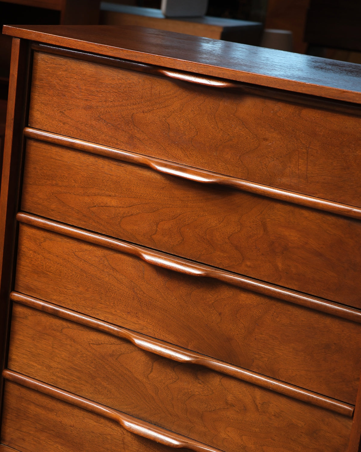 Close-up of the sculpted drawer pulls and grain detail on the walnut tallboy dresser.