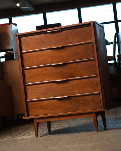 Angled front view of the walnut tallboy dresser showing depth and drawer alignment.