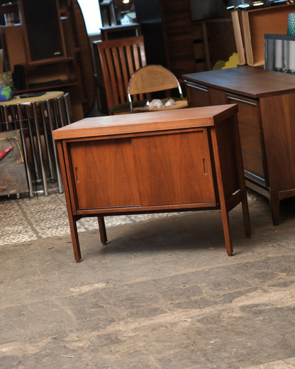 Three-quarter view of the walnut vinyl cabinet showing sliding doors and tapered legs