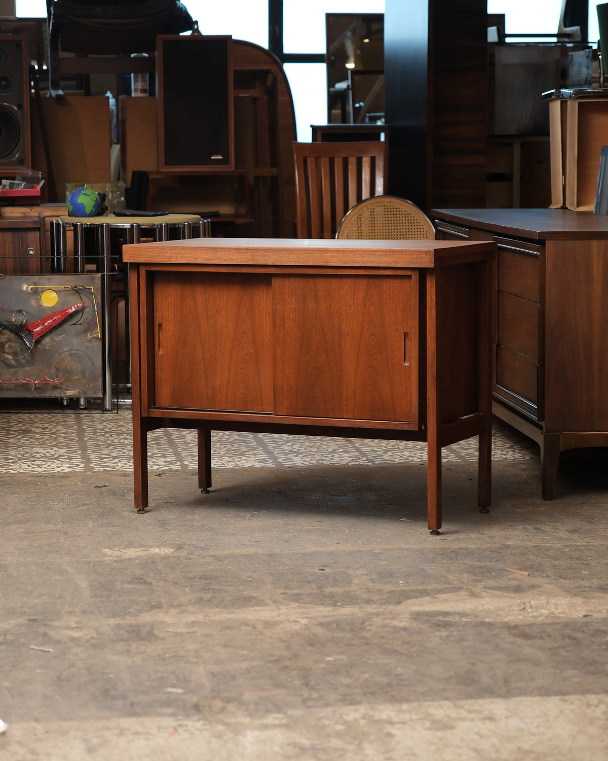 Front view of the walnut cabinet with sliding doors closed, set on tapered legs