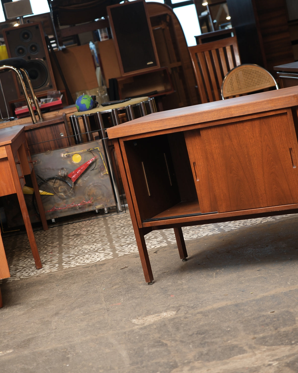 Angled view of the cabinet with one sliding door open, revealing the interior shelf
