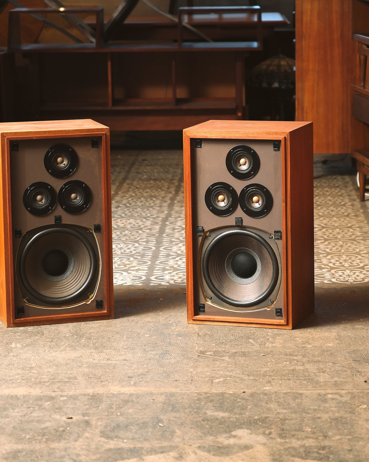 Front view of the walnut speaker pair with grilles off, showing tweeters and woofers side by side.