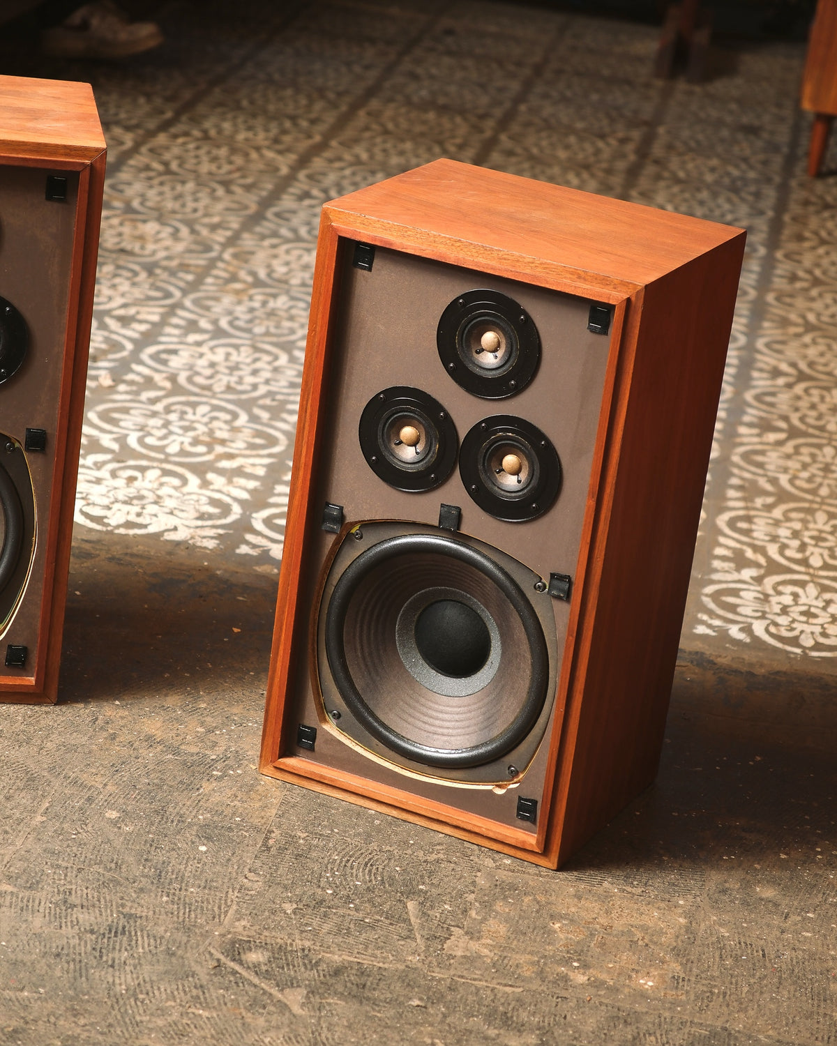 Close-up angled shot of one speaker cabinet with grille removed, showing the three tweeters and woofer.