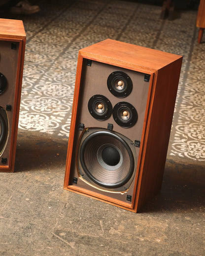 Close-up angled shot of one speaker cabinet with grille removed, showing the three tweeters and woofer.