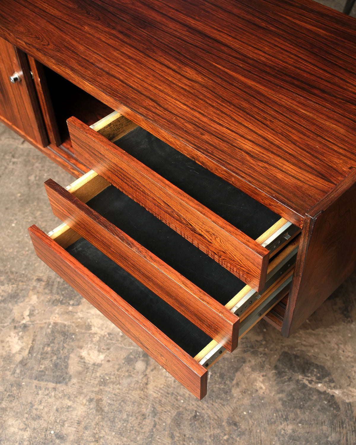 Interior view of the credenza with three drawers open, revealing rosewood fronts and metal slides