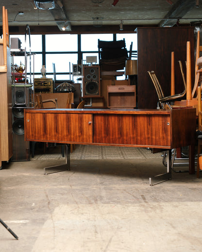 Side view of the rosewood credenza showing its full length and angled chrome leg design