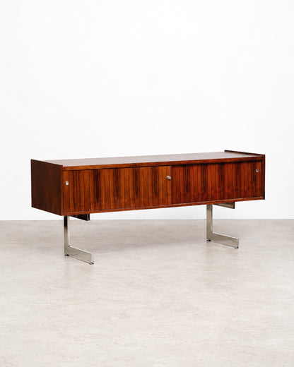 Detail of the chrome leg and base support beneath the rosewood cabinet