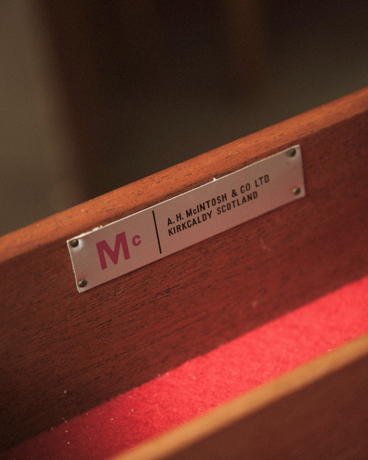 Close-up of the maker's plate reading A.H. McIntosh & Co Ltd, Kirkcaldy, Scotland, mounted inside the drawer.
