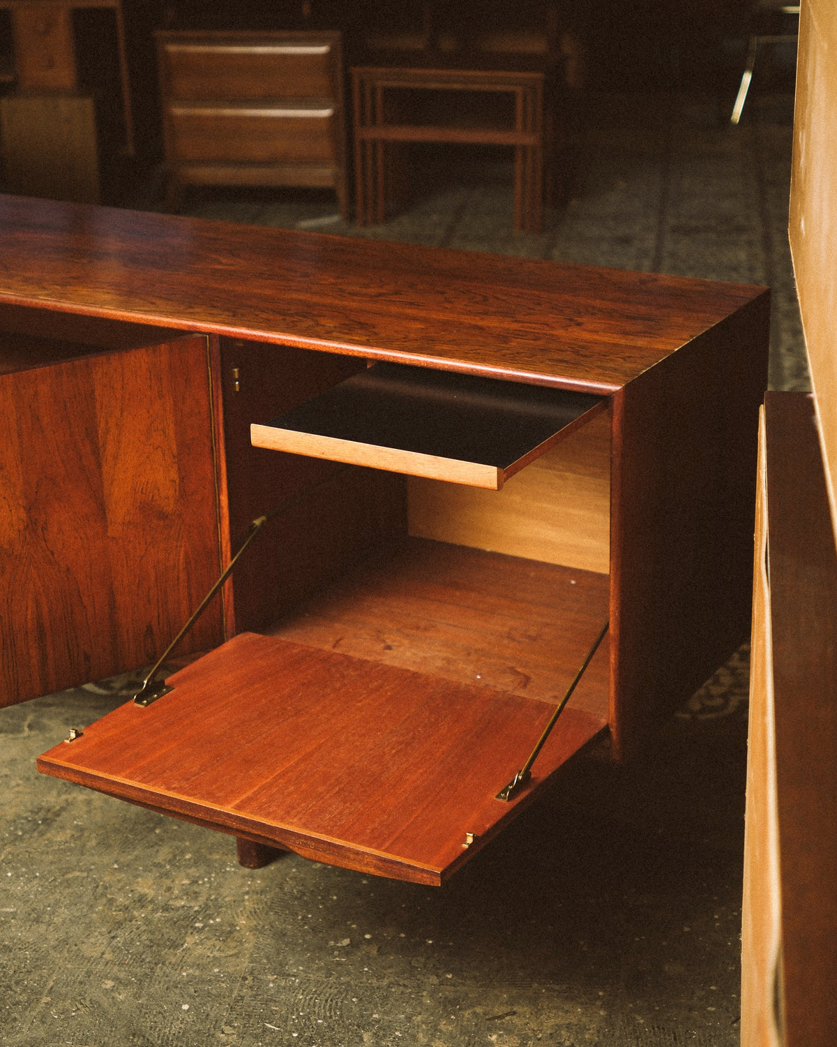 Detail of the drop-front compartment open, showing the interior tray and brass support hinges.