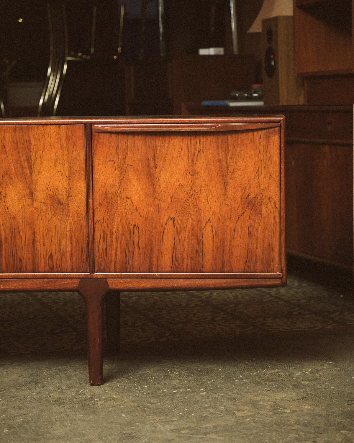 Close-up of the rosewood grain and sculpted pull handle on one of the cabinet doors.