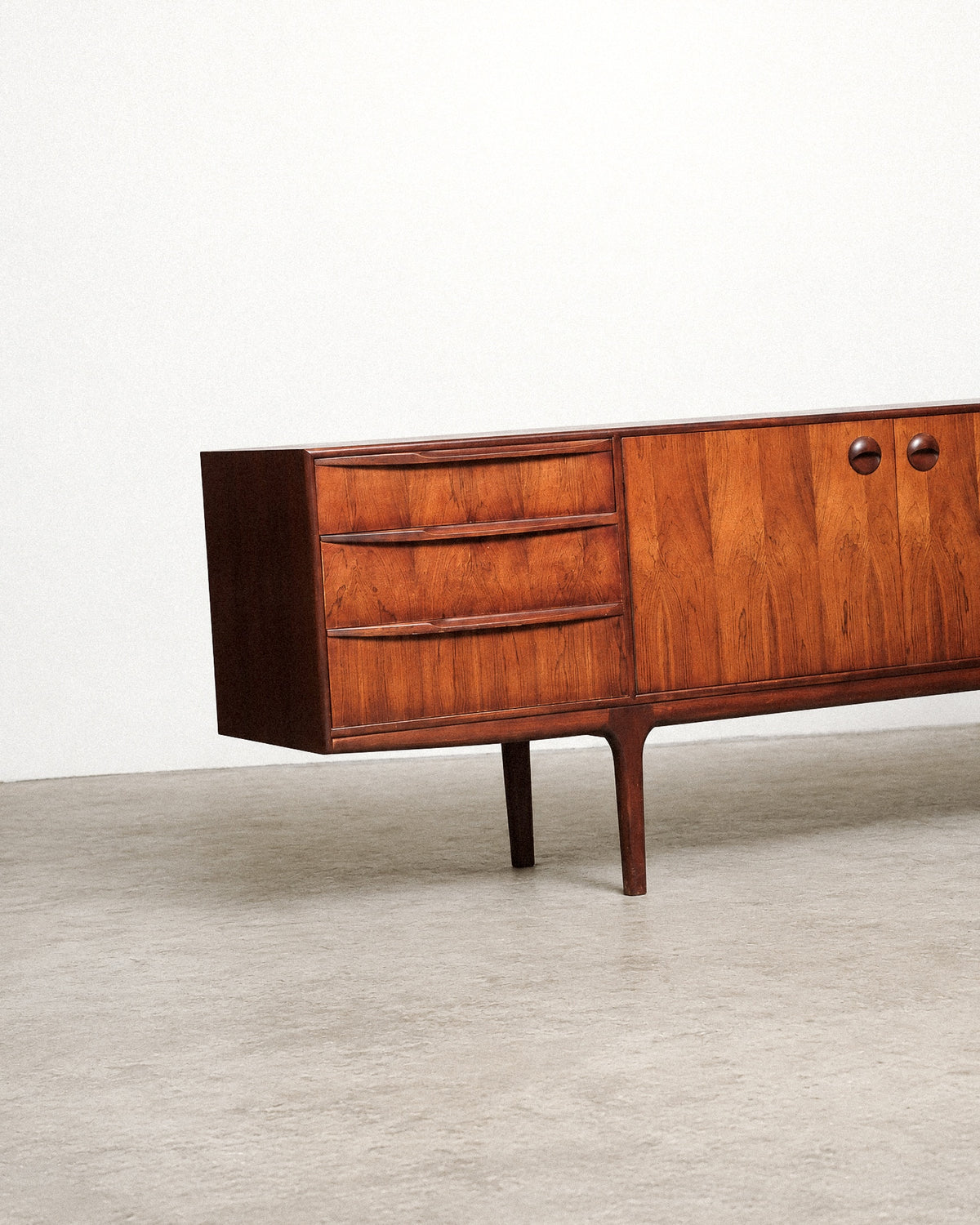 Detail of the drawer fronts showing rosewood grain and sculpted pull handles.