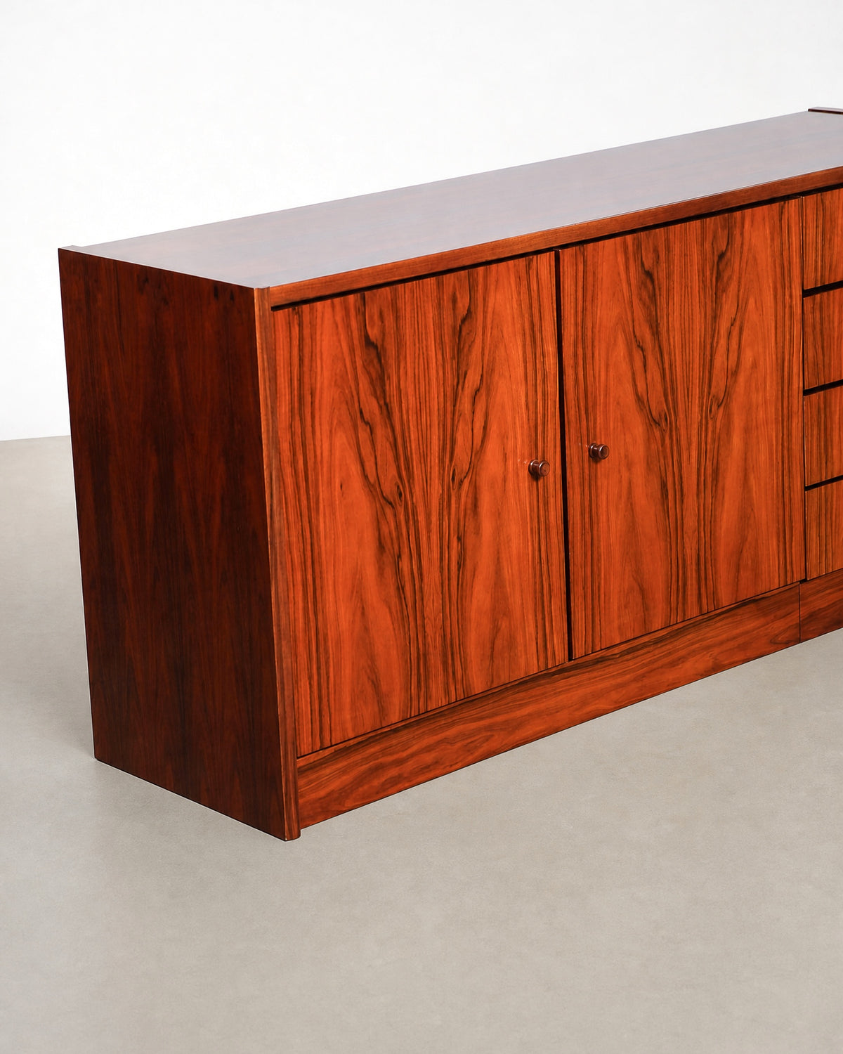Side and front angle highlighting the cabinet doors, drawer stack, and rosewood veneer pattern.