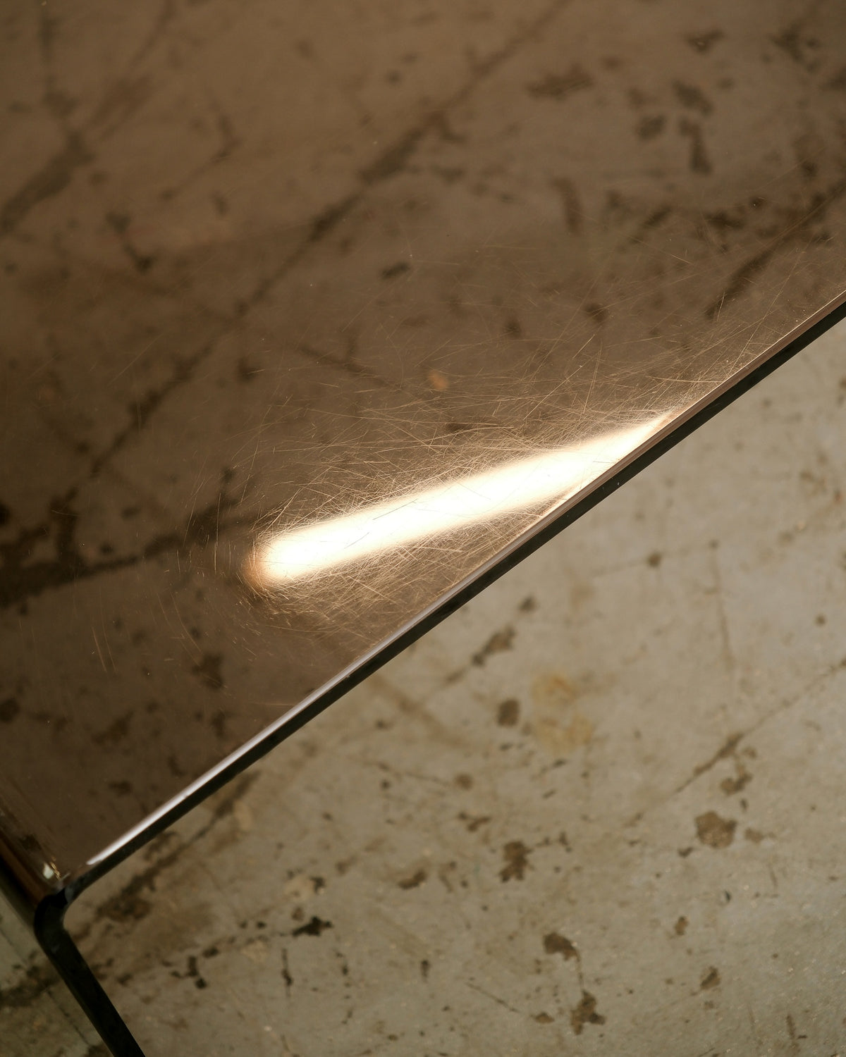Close-up of the smoked lucite corner edge showing surface scratches and light reflection.
