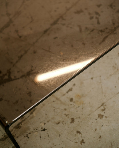 Close-up of the smoked lucite corner edge showing surface scratches and light reflection.