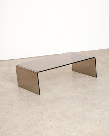 Full side view of the smoked lucite waterfall coffee table against a white wall.