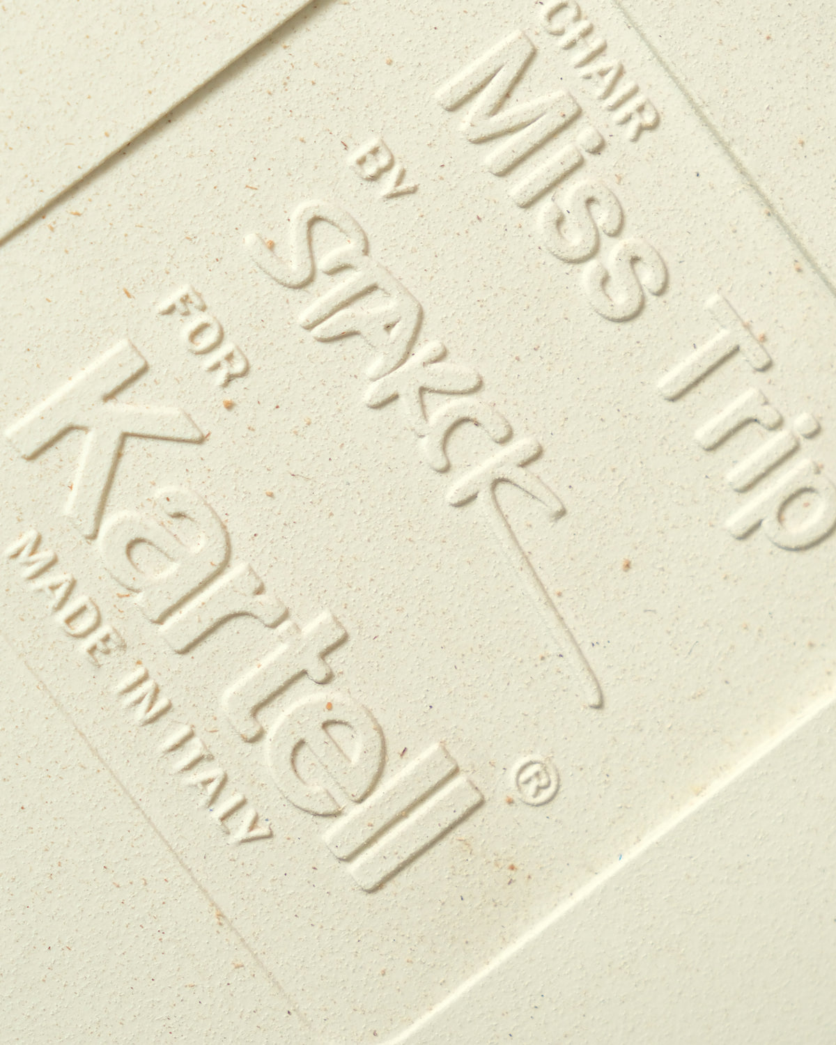 Close-up of embossed maker's mark reading Miss Trip chair by Philippe Starck for Kartell, Made in Italy.