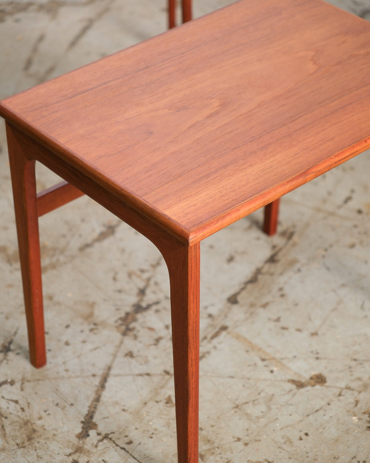 Close-up of the largest nesting table's teak top and tapered leg with sculpted corner joinery