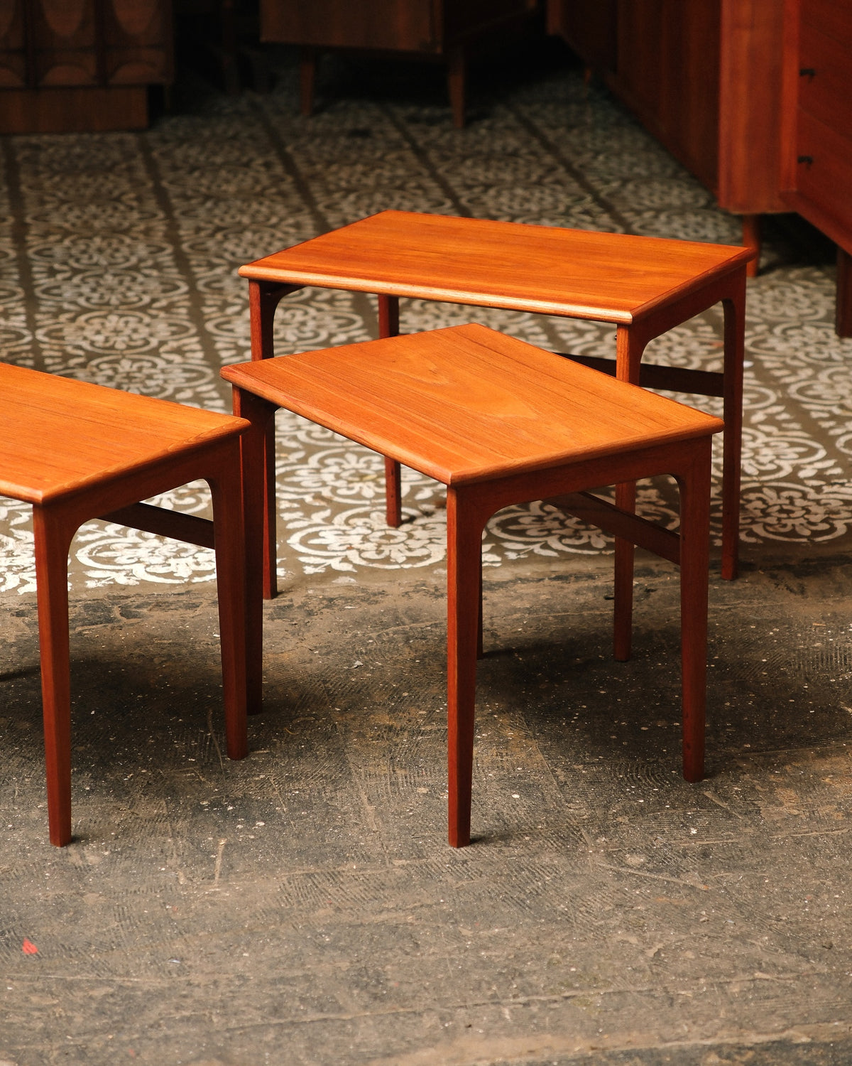 Three nesting tables shown separated at graduated heights on a patterned floor