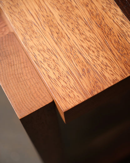Close-up of the two-tone hardwood cabinet's top corner joinery and grain detail.