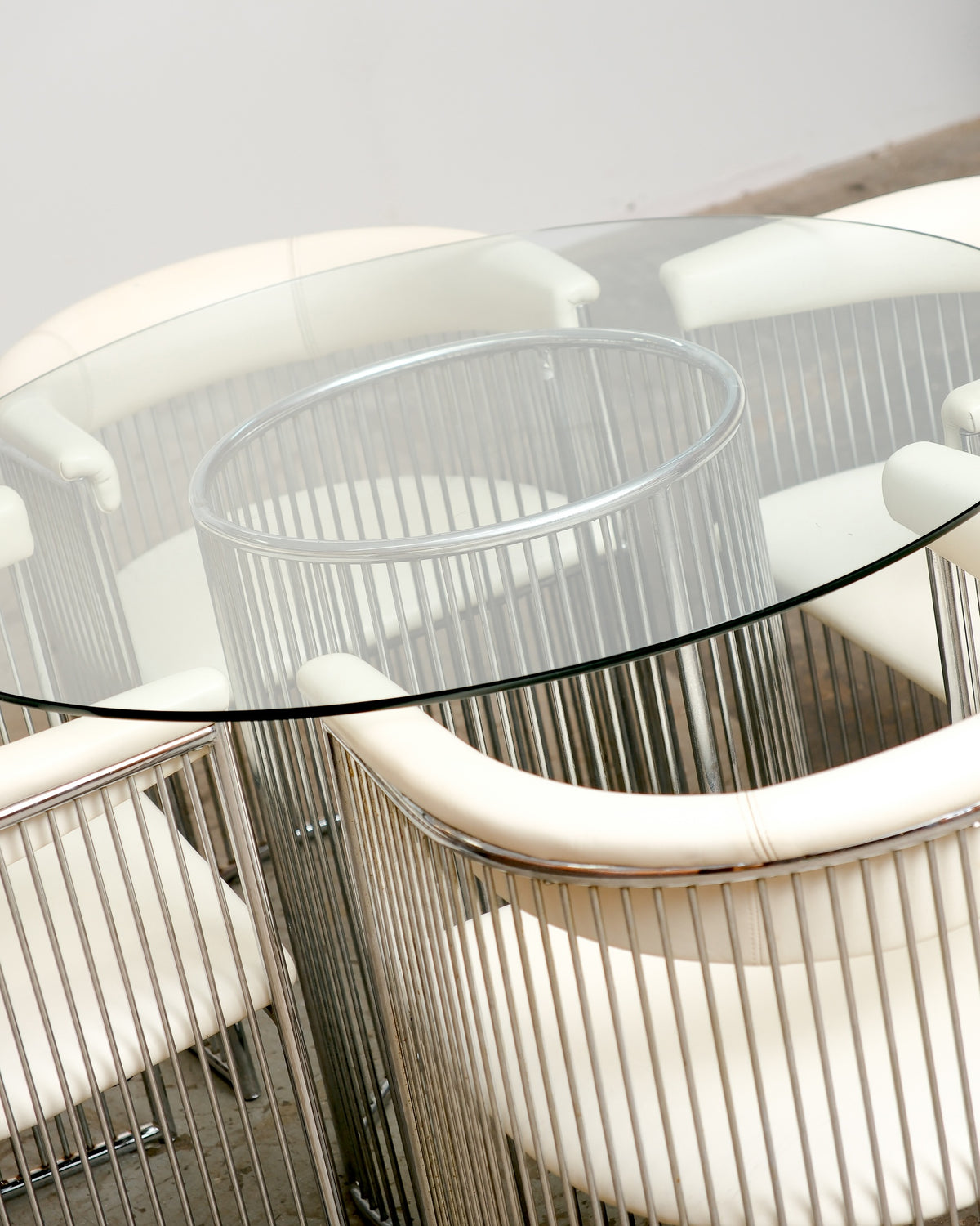 Overhead view of the round glass table top showing the chrome rod base and surrounding chairs.
