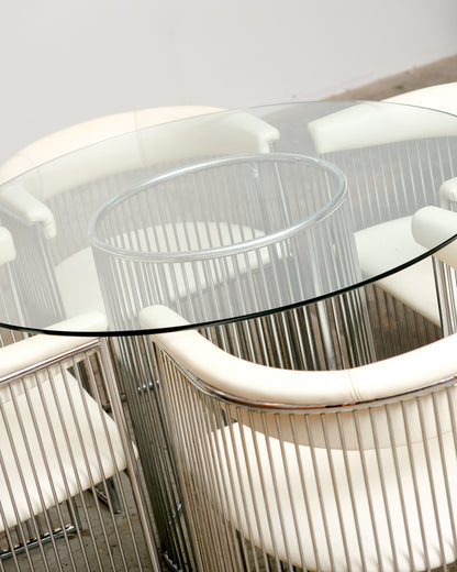 Overhead view of the round glass table top showing the chrome rod base and surrounding chairs.