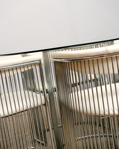 Detail of the chrome rod chair backs and glass table edge, showing joinery and finish.