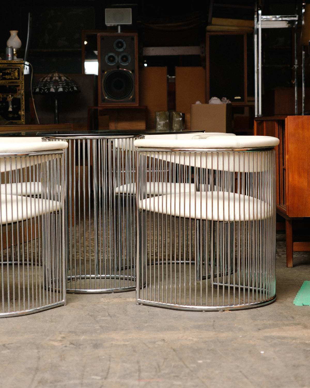 Full view of the chrome dining set in a warehouse setting, showing table and chair silhouettes.