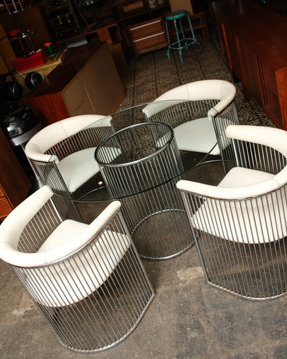 Overhead angle of the complete dining set with four chairs arranged around the round glass table.