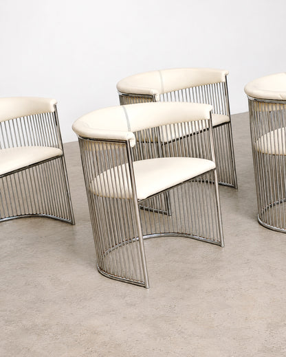 Detail of a chair's curved chrome armrest and cream leatherette seat.
