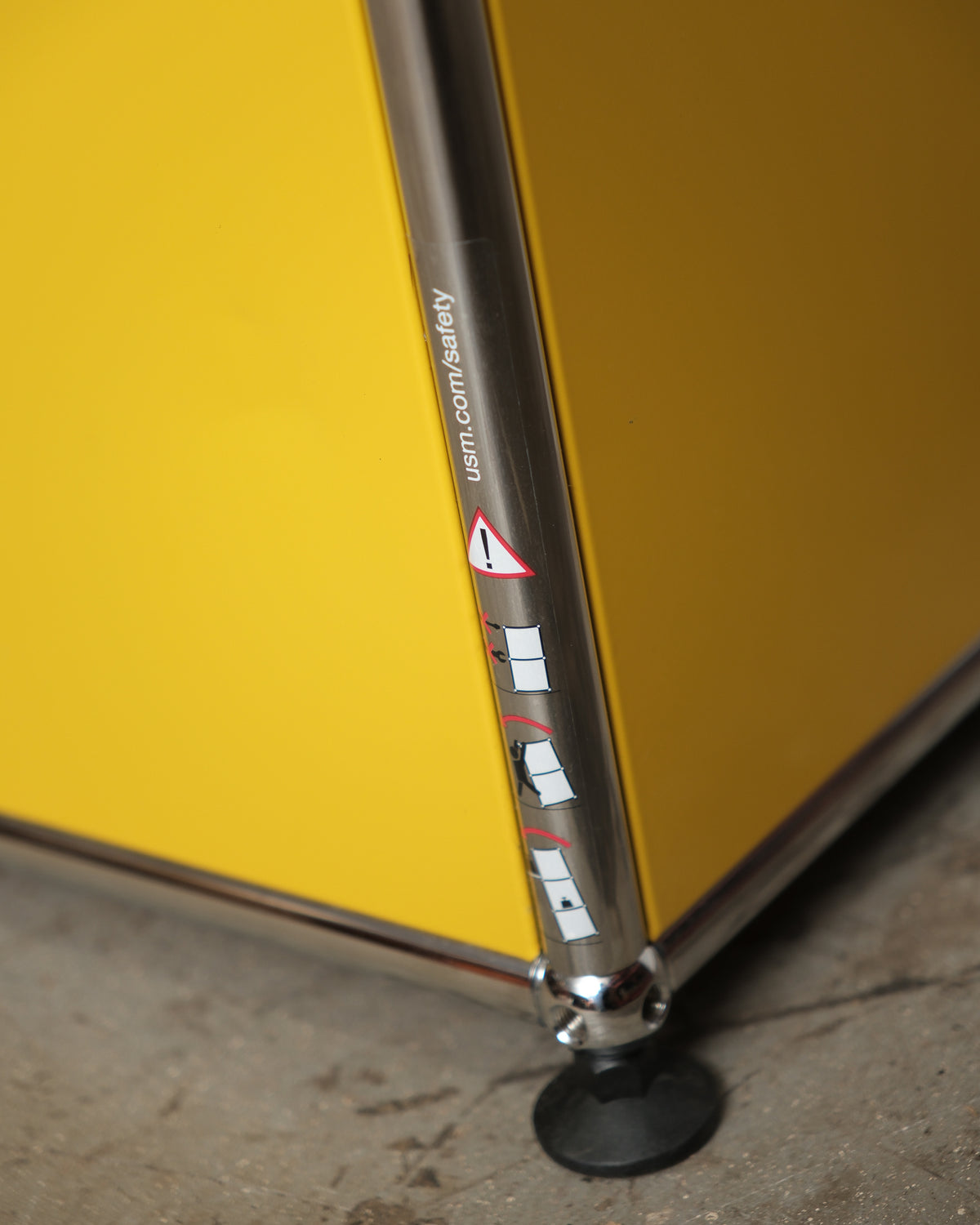 Close-up of the chrome leg and adjustable foot with USM safety sticker.