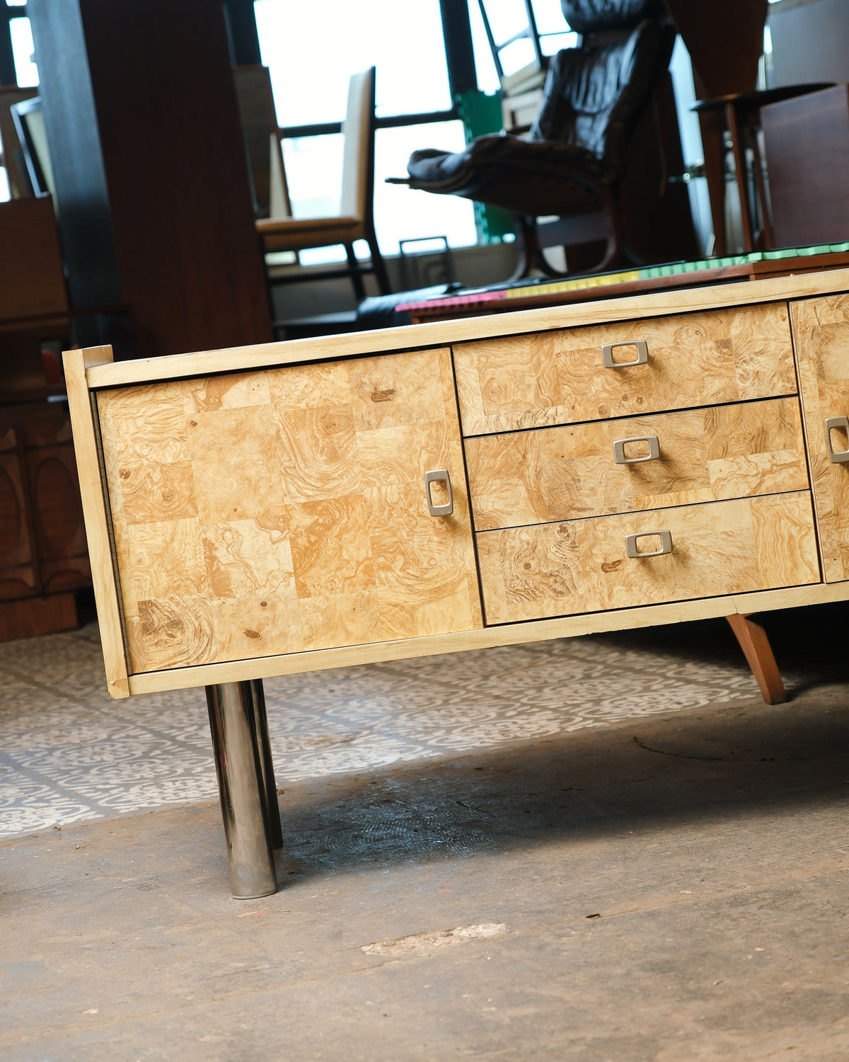 Side angle of the sideboard showing the burl door, drawers, and adjacent cabinet.