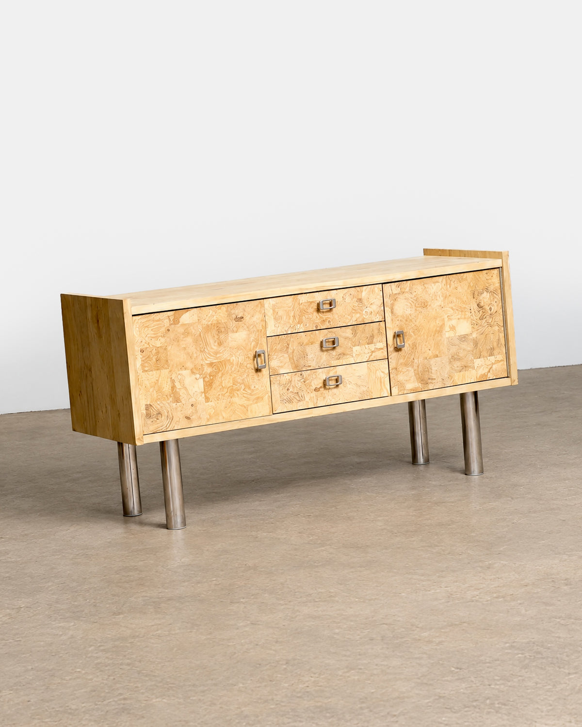 Detail of the sculpted metal drawer pull against the burl wood surface.