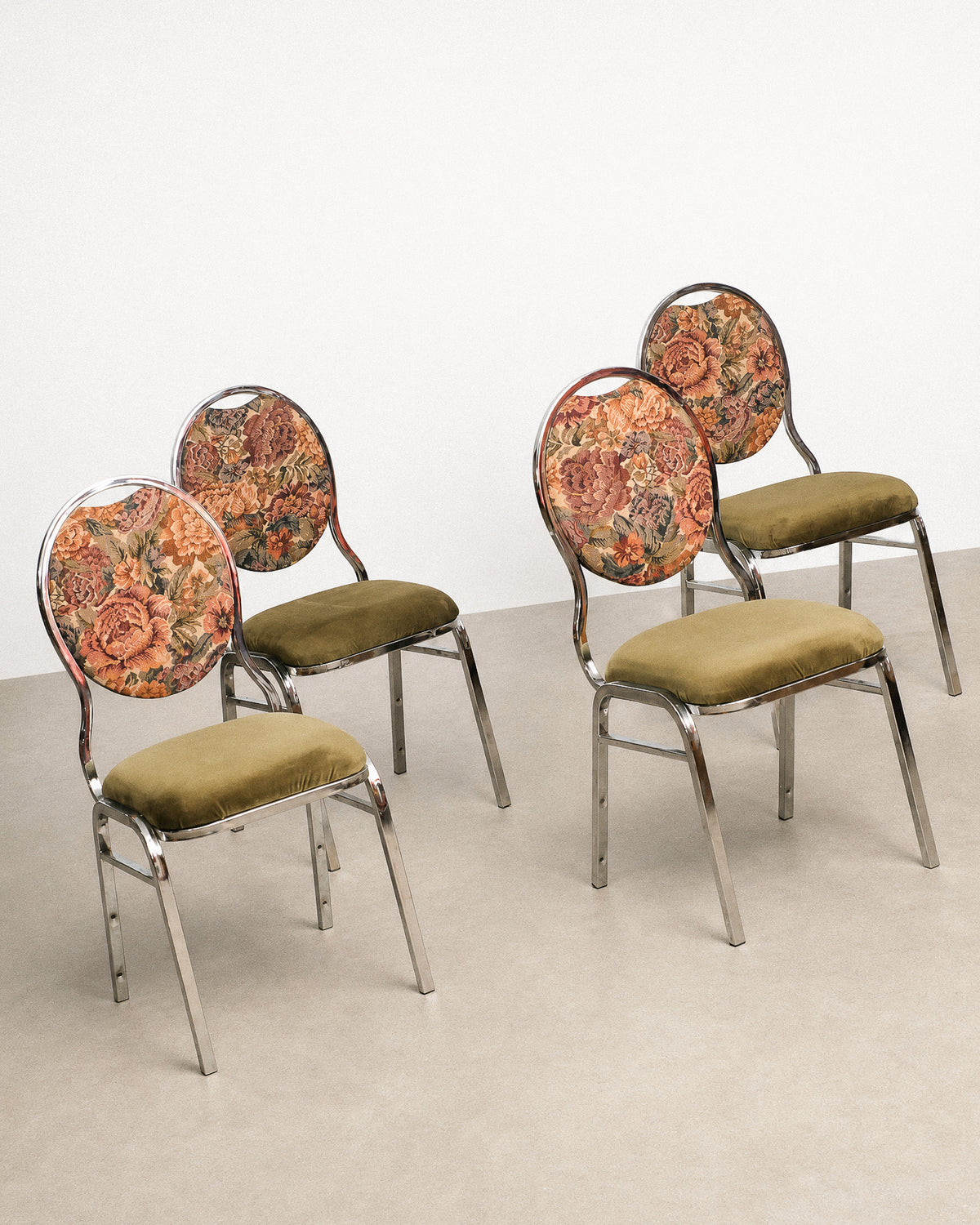 Four floral-patterned chairs with green cushions on a plain background