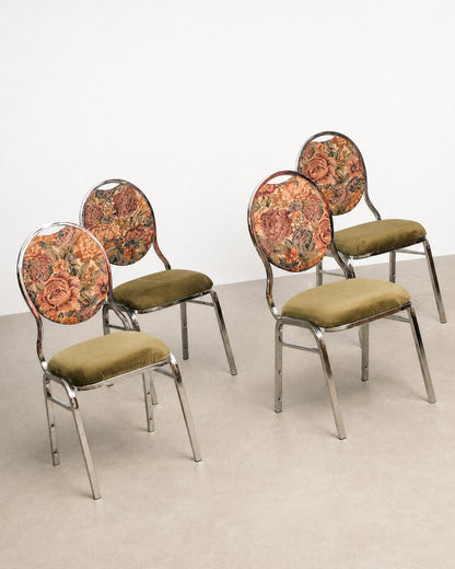 Four floral-patterned chairs with green cushions on a plain background
