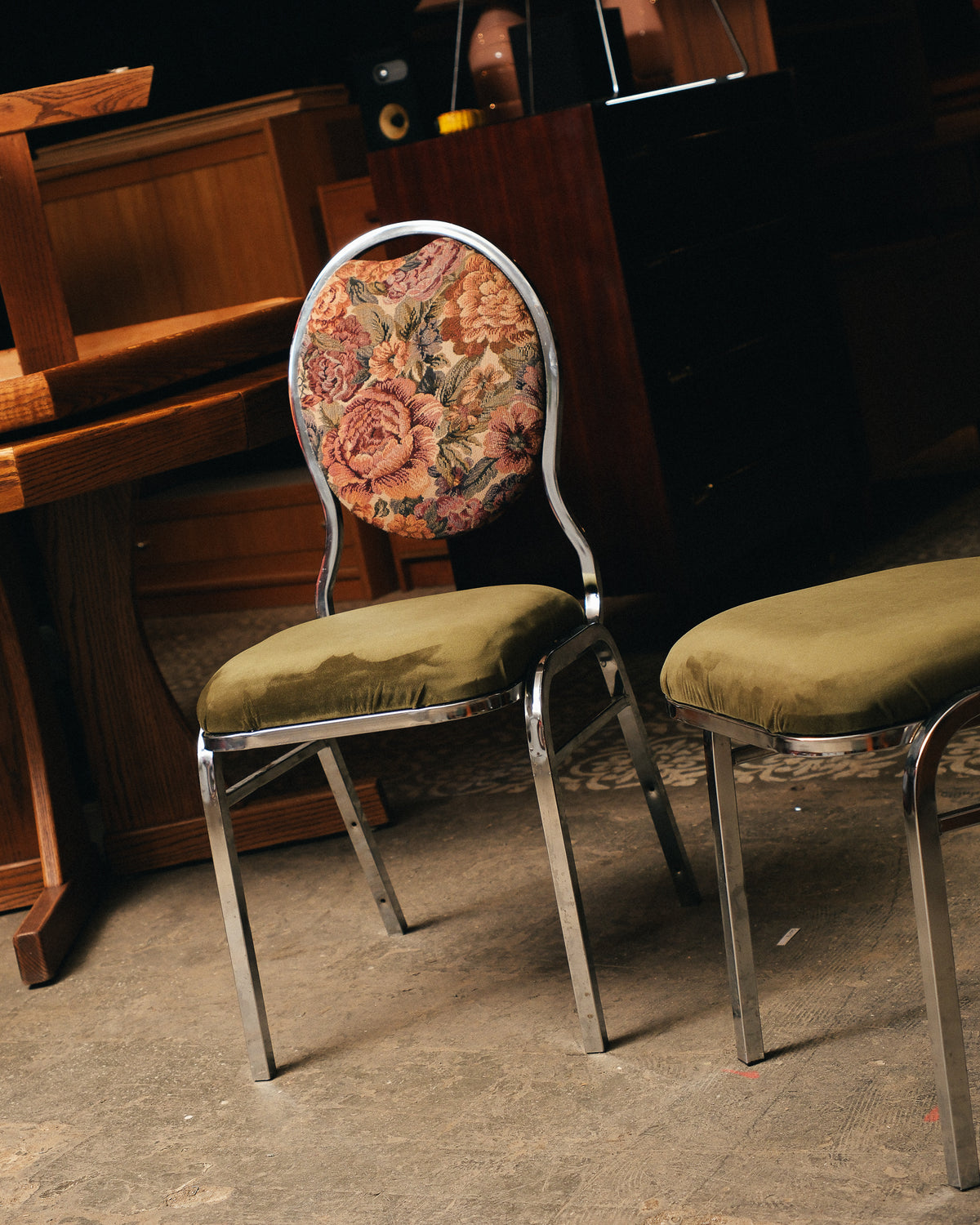 Two chairs with floral backrest and green seats in front of a wooden piano.