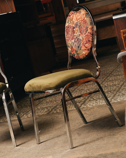 Vintage chair with floral backrest and green cushion on a wooden floor.