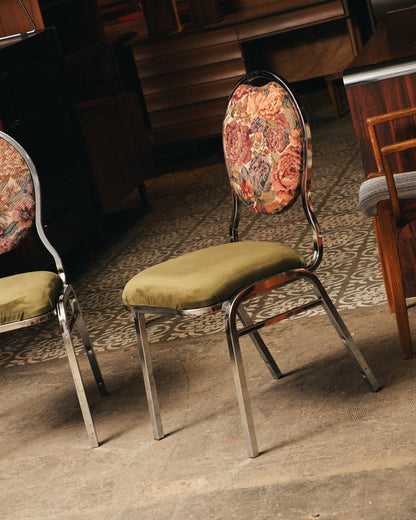 Vintage chairs with floral backrests and green seats on a patterned floor.