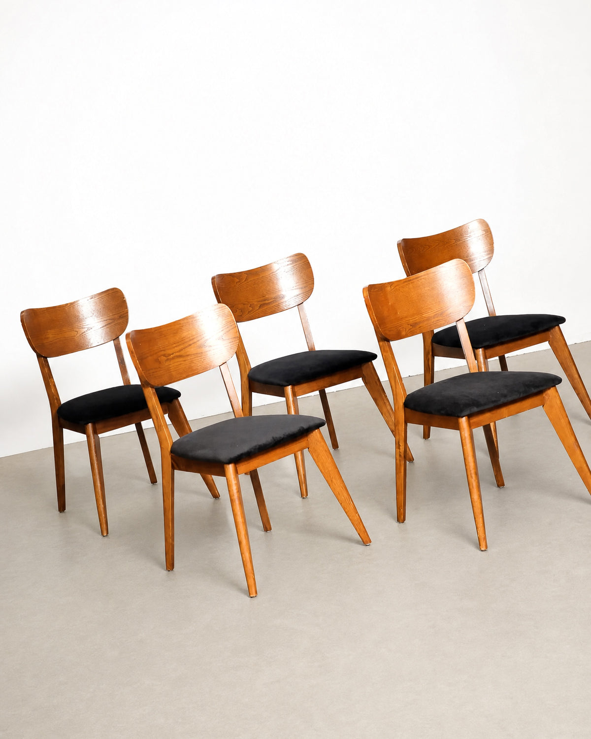 Set of six dining chairs arranged together showing curved backs, tapered legs, and black velvet seats.