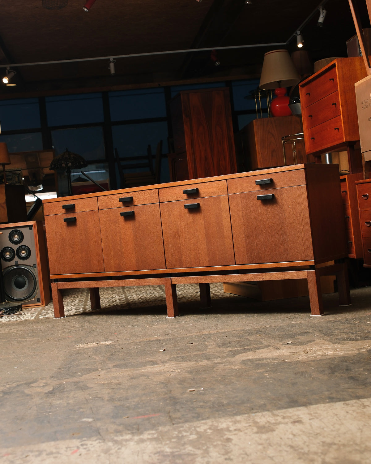 Low front-facing angle of the oak sideboard showing its stepped leg base and black squared pulls.