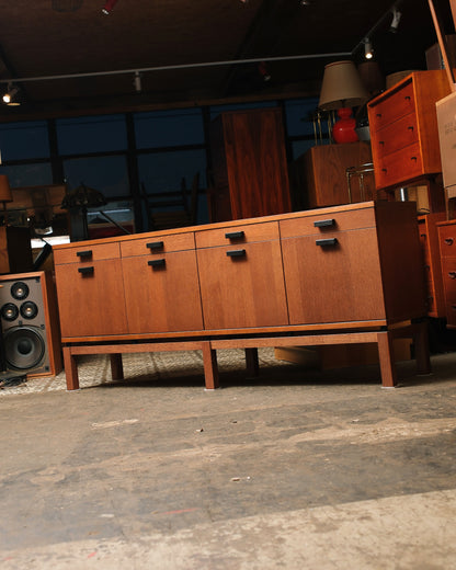 Low front-facing angle of the oak sideboard showing its stepped leg base and black squared pulls.