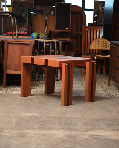 Vintage square coffee table shown in a furniture showroom setting among other pieces.
