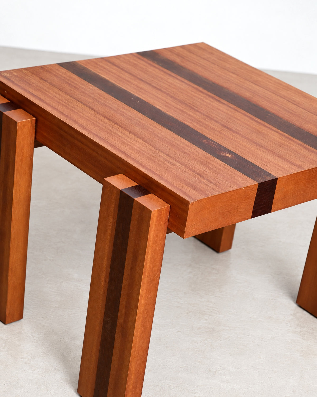 Close-up studio shot of the tabletop and leg joinery highlighting the wood grain and inlay stripes.