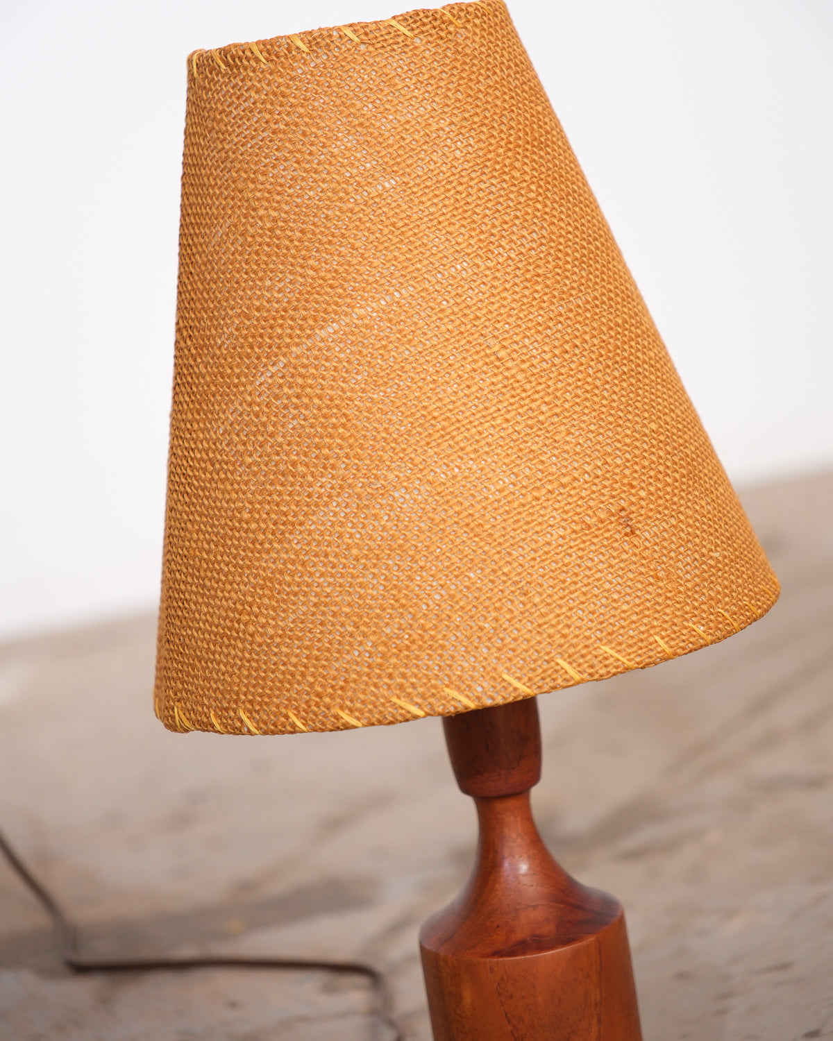 Close-up of the woven wicker lamp shade and turned walnut neck.