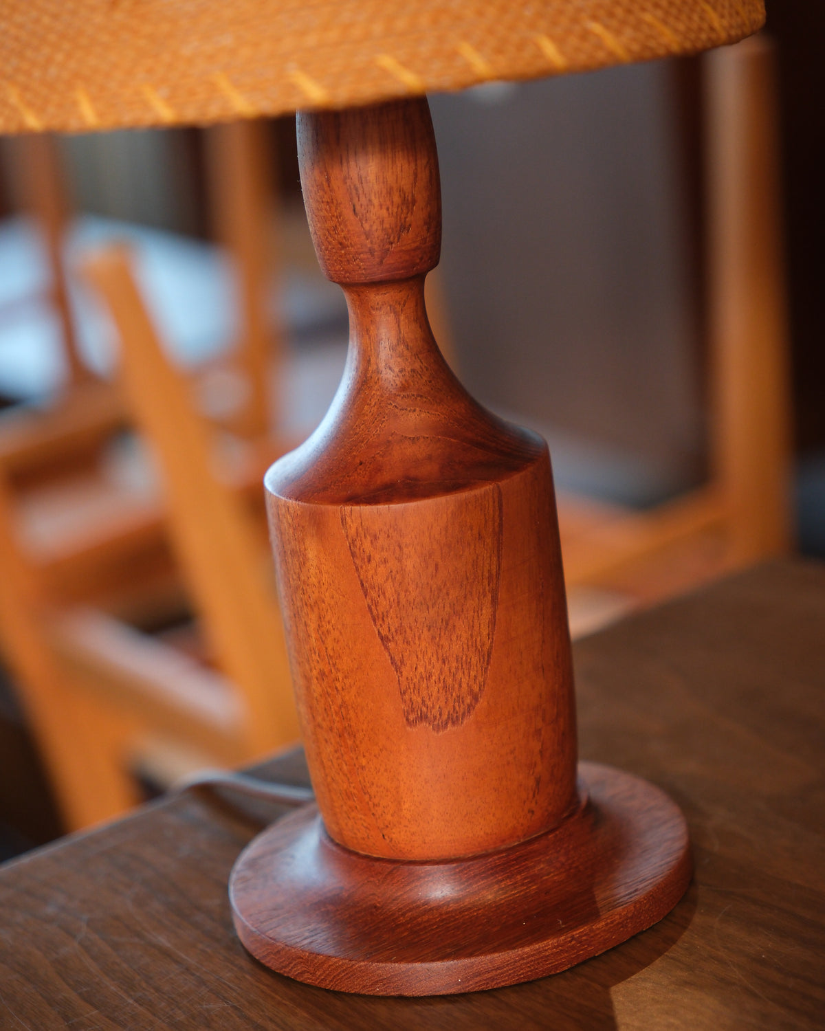 Detail of the turned walnut base showing wood grain and stand.